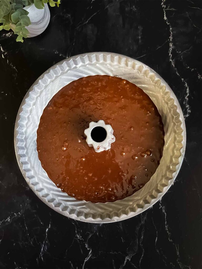 Chocolate bundt cake batter in a bundt pan on a dark surface.