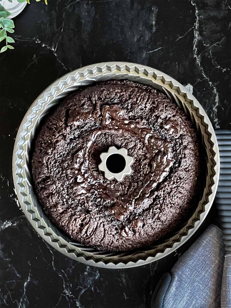 Baked chocolate bundt cake in the pan on a dark surface.