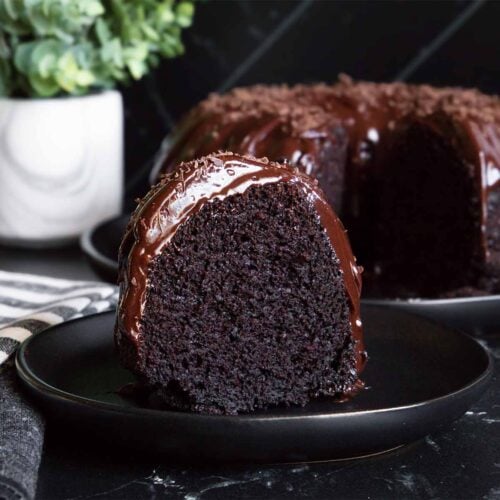 A slice of chocolate bundt cake on a dark plate.