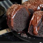 A slice of chocolate bundt cake on a dark plate.