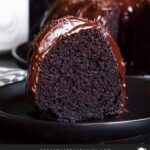 A slice of chocolate bundt cake on a dark plate.