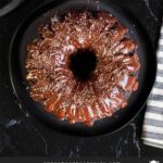 A chocolate bundt cake on a dark plate.