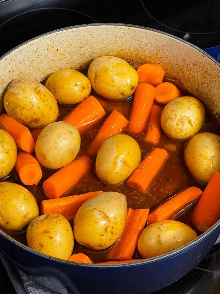 Potatoes and carrots added to the dutch oven with the pot roast.