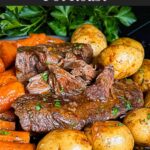 Classic pot roast with potatoes and carrots on a dark plate on a dark surface.