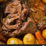 Classic pot roast with potatoes and carrots on a dark plate on a dark surface.