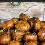 Garlic butter roasted mushrooms in a dark bowl on a dark surface.