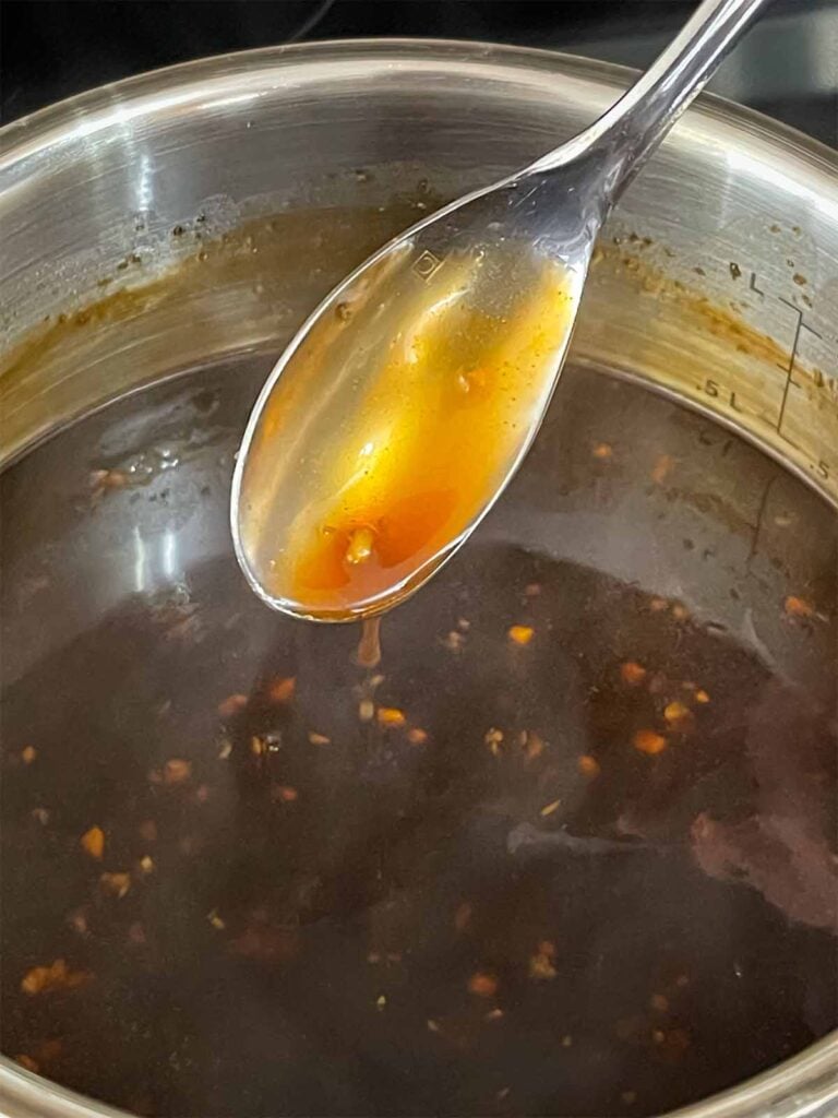 Bourbon sauce, cooked, with a spoon showing off the thickness.