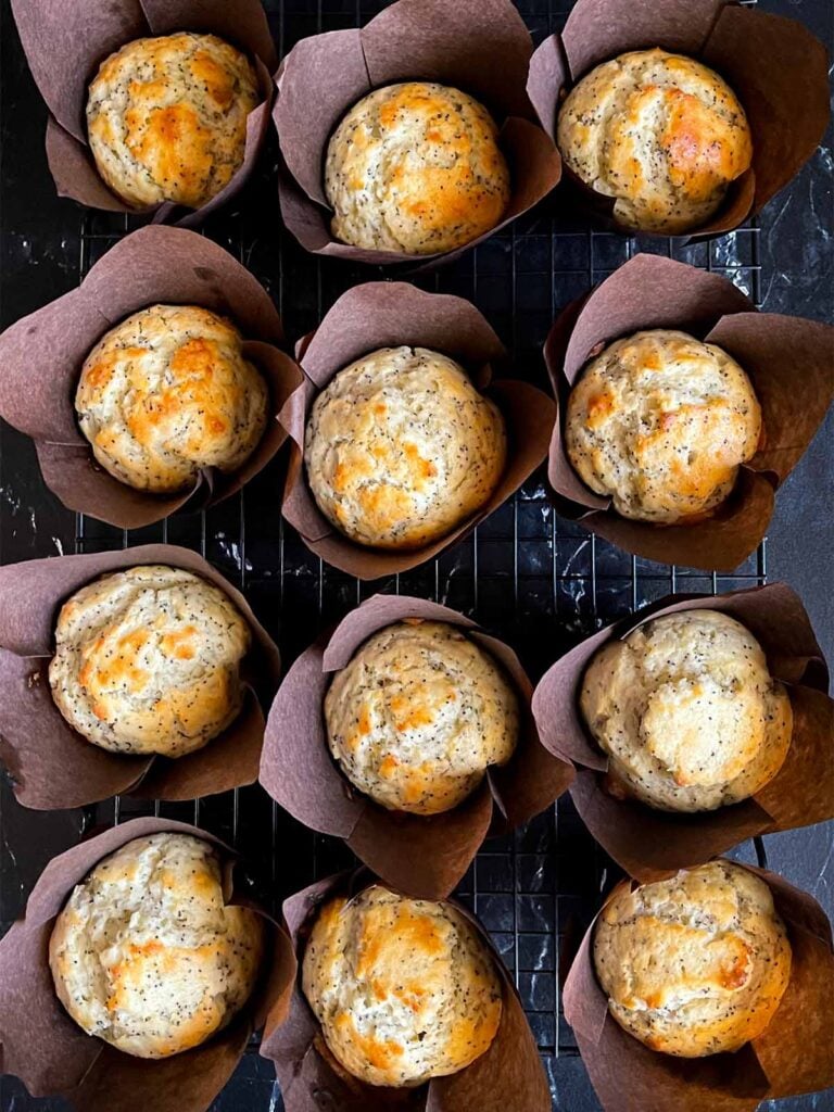 Baked lemon poppy seed muffins in a paper liners on a wire rack.
