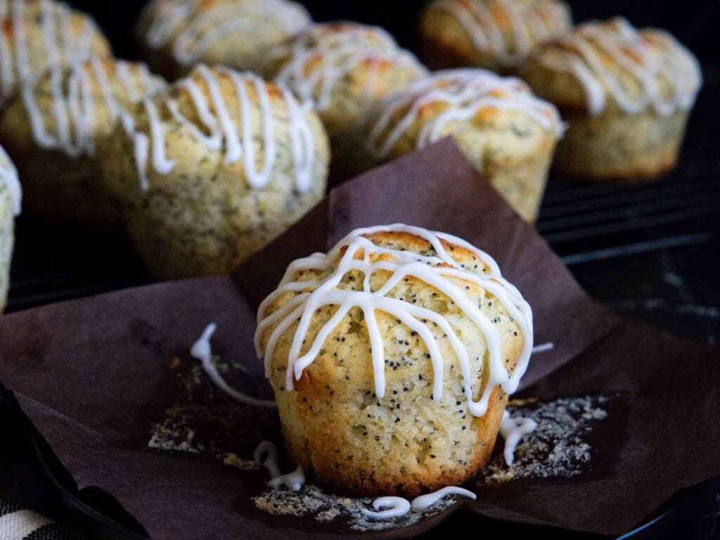 Lemon poppy seed muffin on a dark plate on a dark surface.