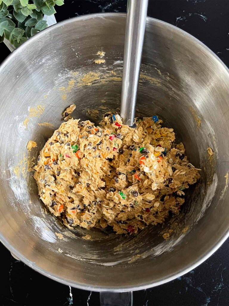 Monster cookie dough in a metal mixing bowl.