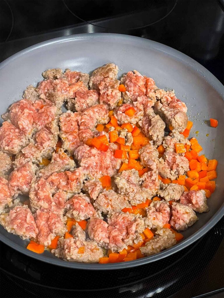 Ground sausage and red bell pepper in a skillet.