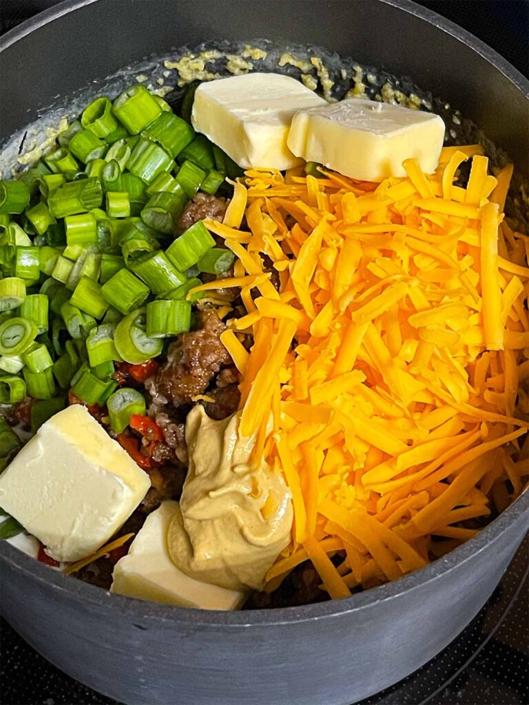 Additional items being tossed into a saucepan of grits.