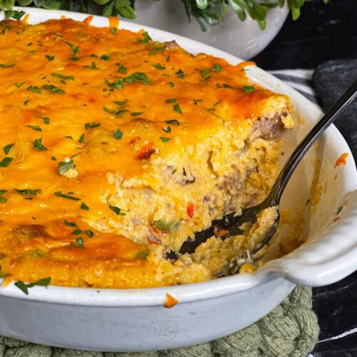 Baked sausage and cheese grits in a casserole dish with a serving cut out.
