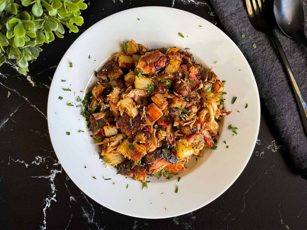 Smoked pulled pork hash garnished with parsley in a white bowl.