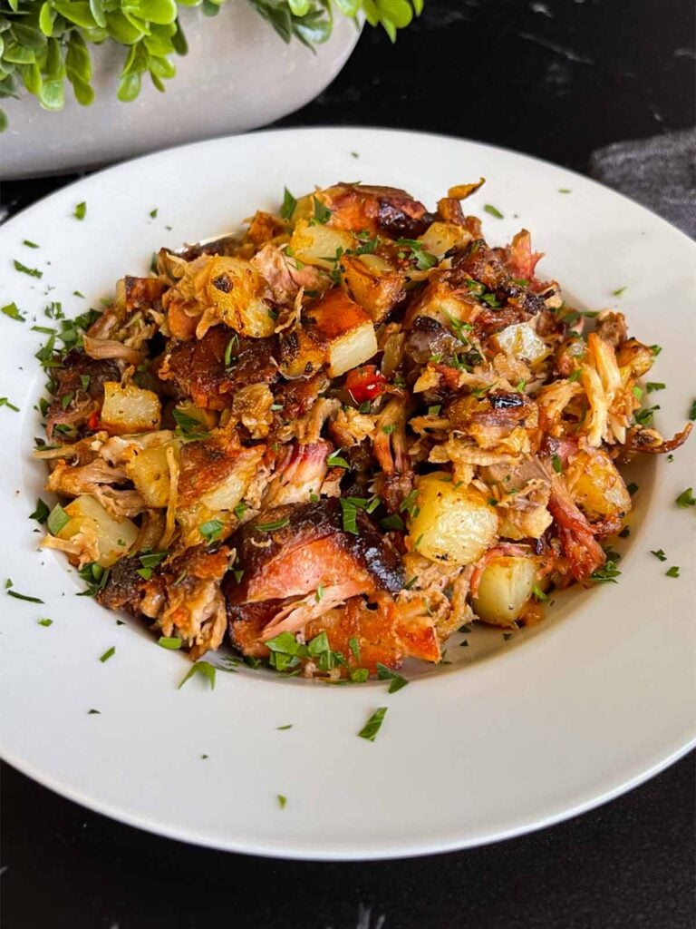 Smoked pulled pork hash garnished with parsley in a white bowl.