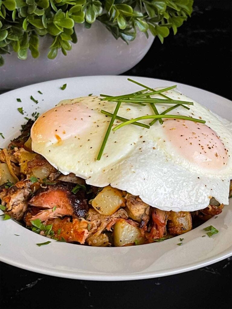 Smoked pulled pork hash garnished with parsley in a white bowl.