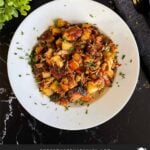 Smoked pulled pork hash garnished with parsley in a white bowl.