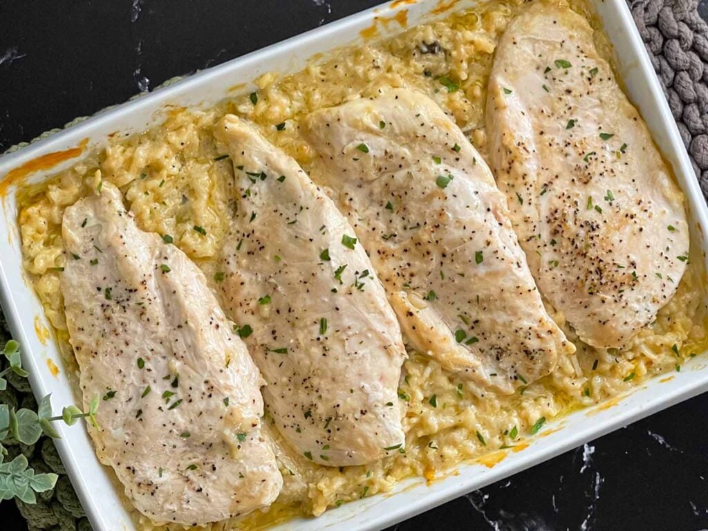 Chicken and rice casserole in a light baking dish on a dark surface.