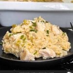 Chicken and rice casserole garnished with chopped parsley on a dark plate on a dark surface.