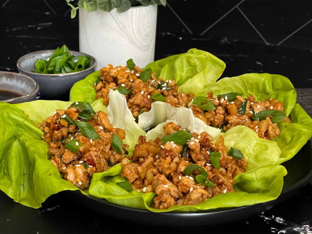 Chicken lettuce wraps on a dark plate.