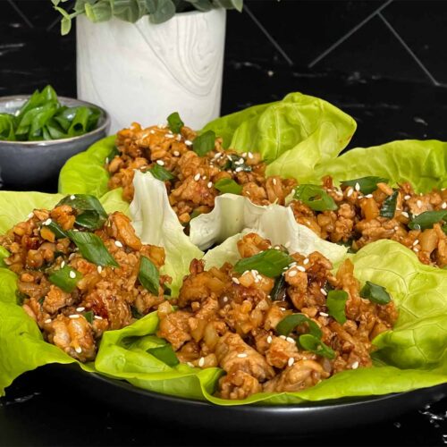 Chicken lettuce wraps on a dark plate.