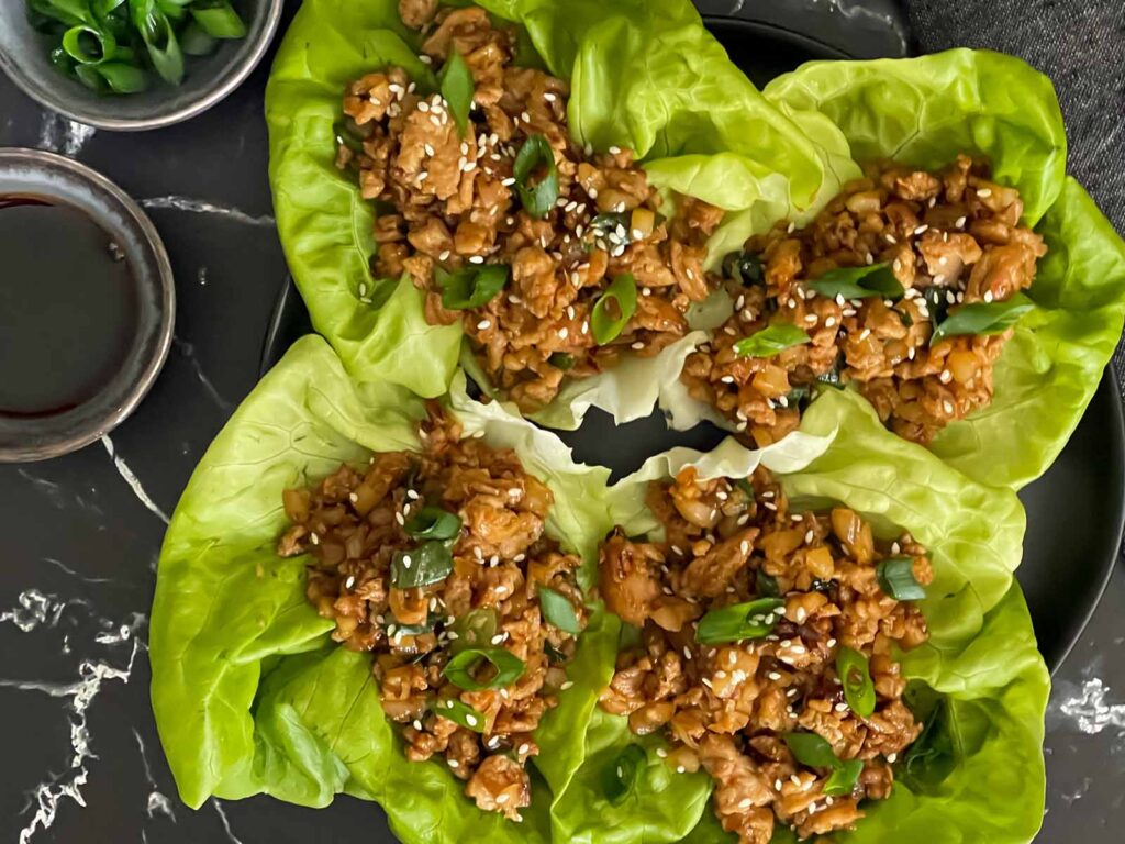 Chicken lettuce wraps on a dark plate.