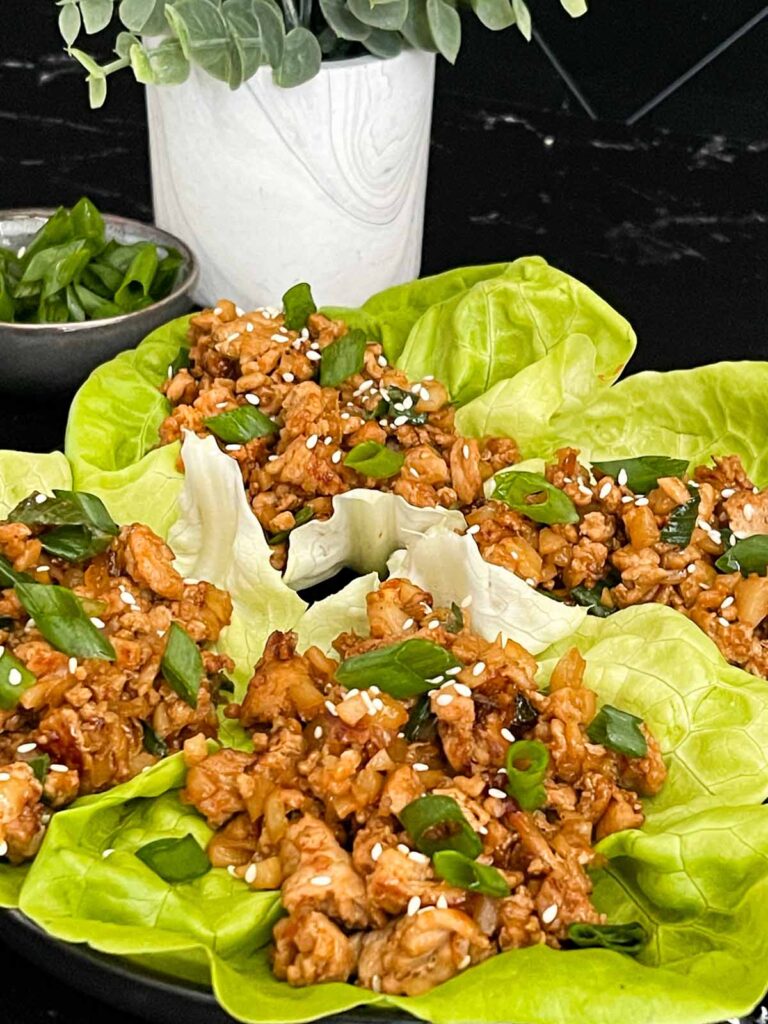 Chicken lettuce wraps on a dark plate.