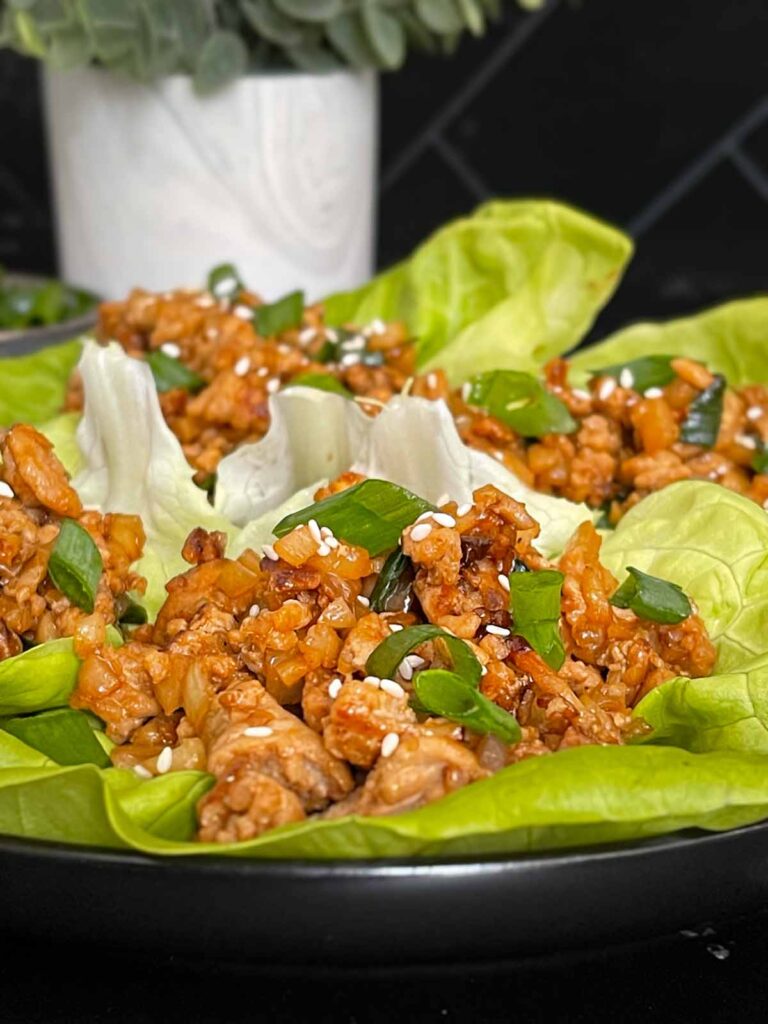 Chicken lettuce wraps on a dark plate.