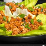 Chicken lettuce wraps on a dark plate.