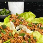 Chicken lettuce wraps on a dark plate.