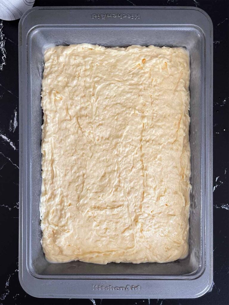 Coconut sheet cake batter spread evenly in a 9x13 baking pan.