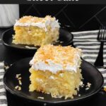 Coconut sheet cake slice on a dark plate on a dark surface.