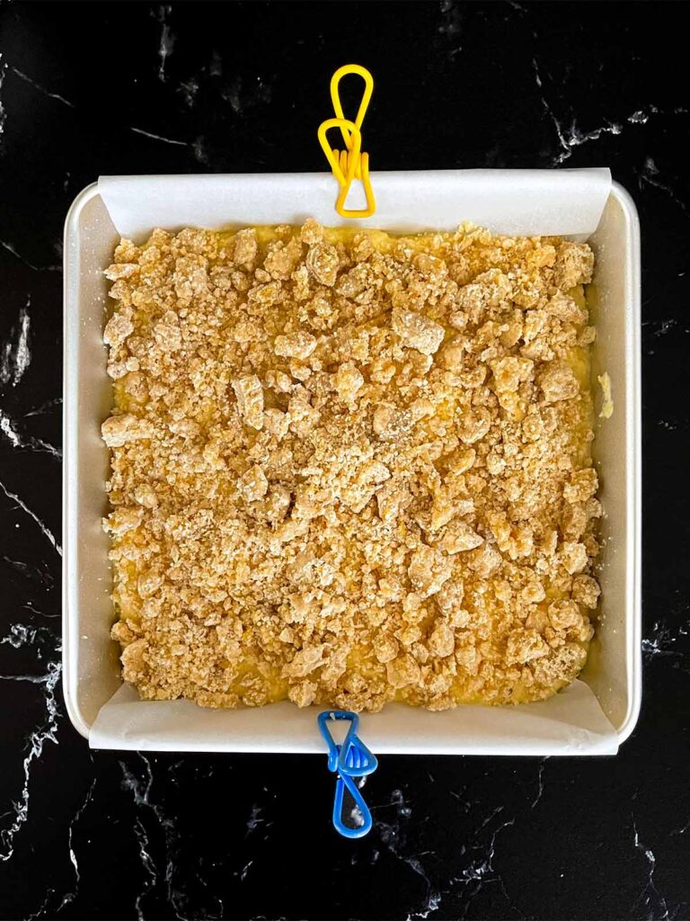 Crumble sprinkled over the lemon crumb cake batter in the baking pan.