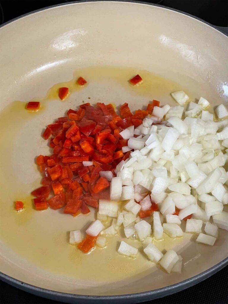 Onion and red bell pepper in a skillet.