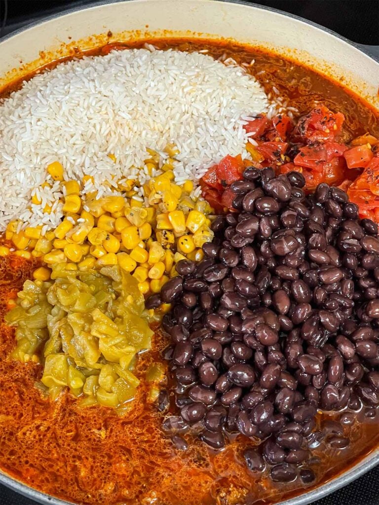 Multiple ingredients being added to the Mexican ground beef mixture.