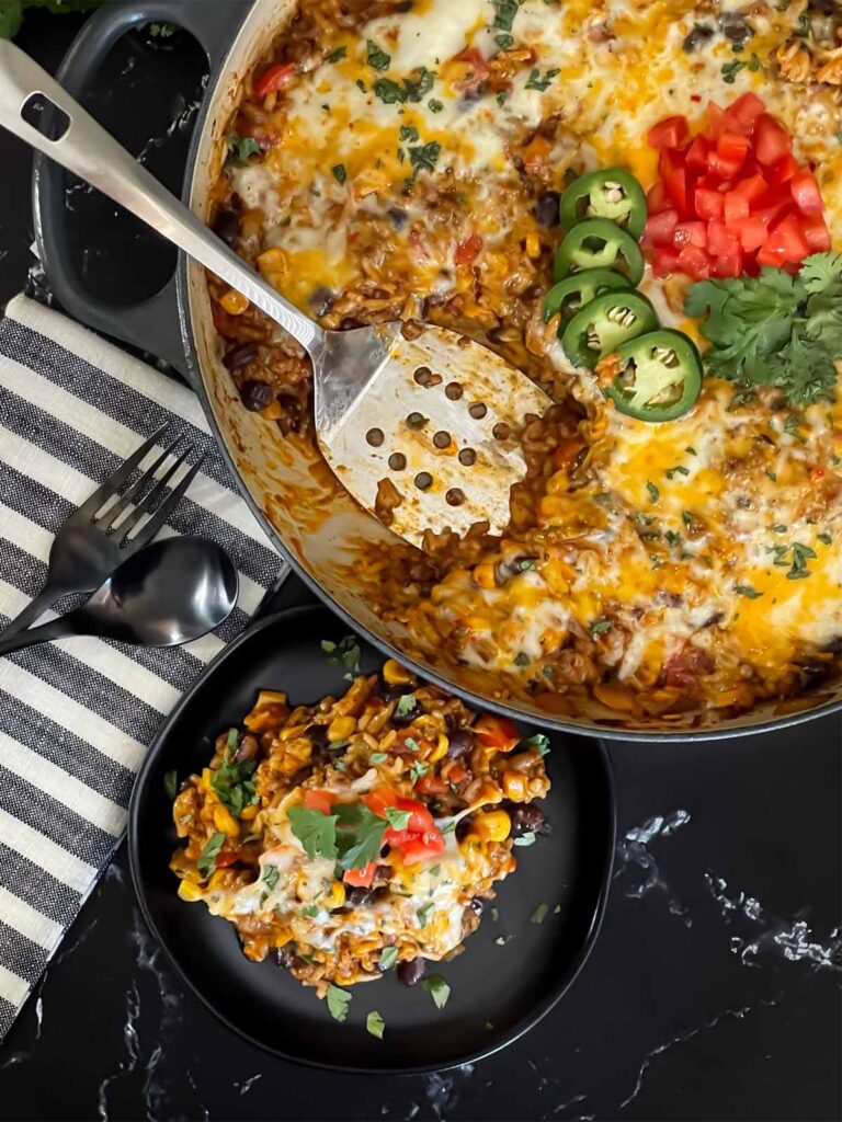 Mexican ground beef with rice with a serving on a dark plate.