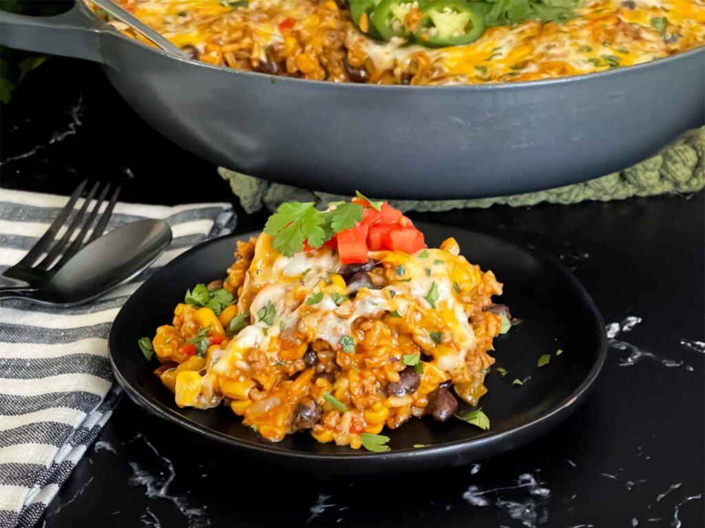 Mexican ground beef with rice with a serving on a dark plate.