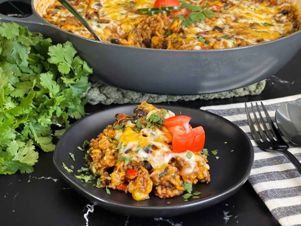 Mexican ground beef with rice with a serving on a dark plate.