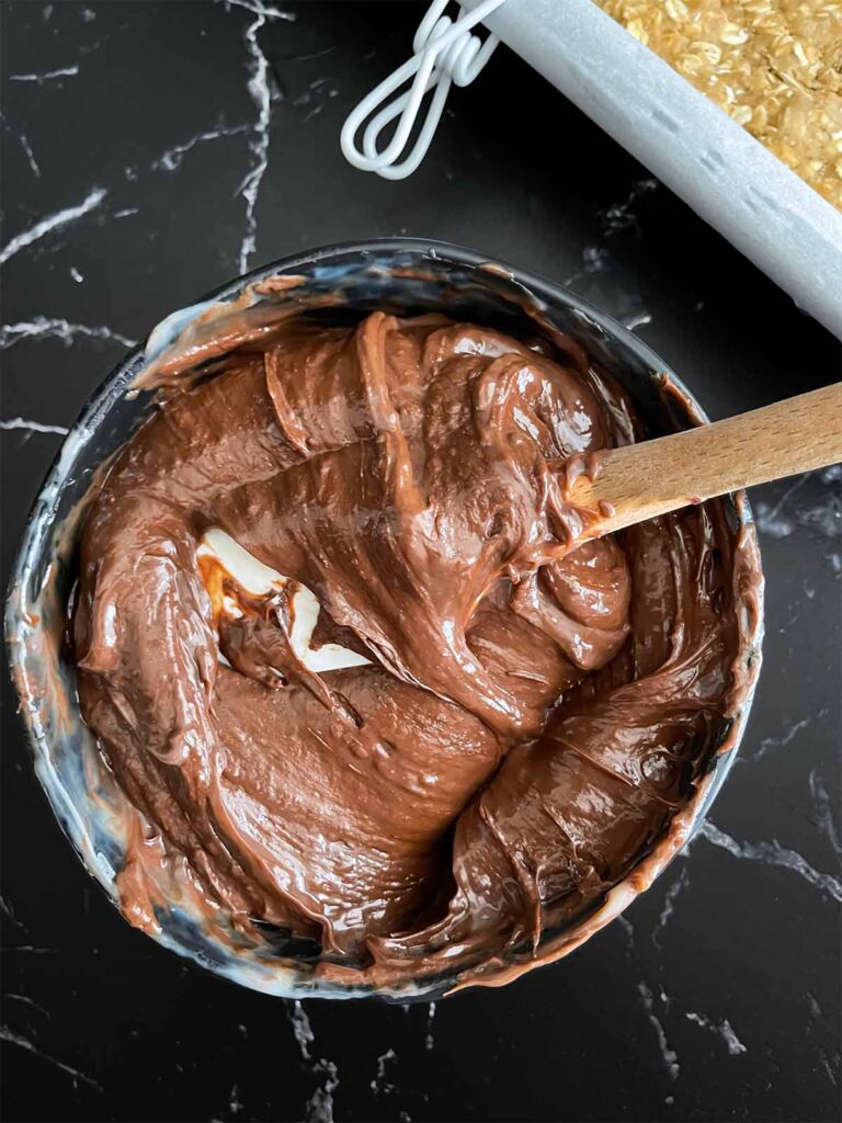 Fudge ingredients melted in a dark bowl on a dark surface.