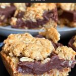 Oatmeal fudge bars on a dark surface in front of a plate of more bars.