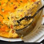 Sausage and cheese grits casserole in a white baking dish with a portion served.