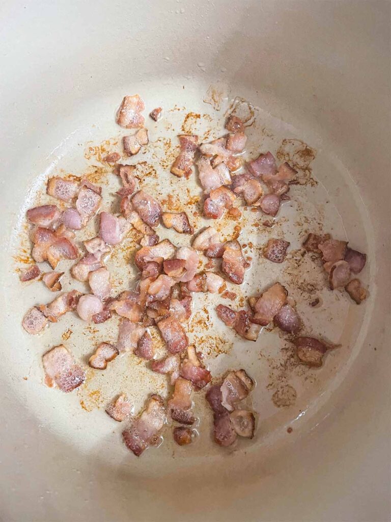Chopped bacon frying in a dutch oven for southern green beans and potatoes recipe.