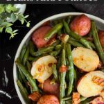 Southern green beans and potatoes in a round light colored bowl on a dark surface.