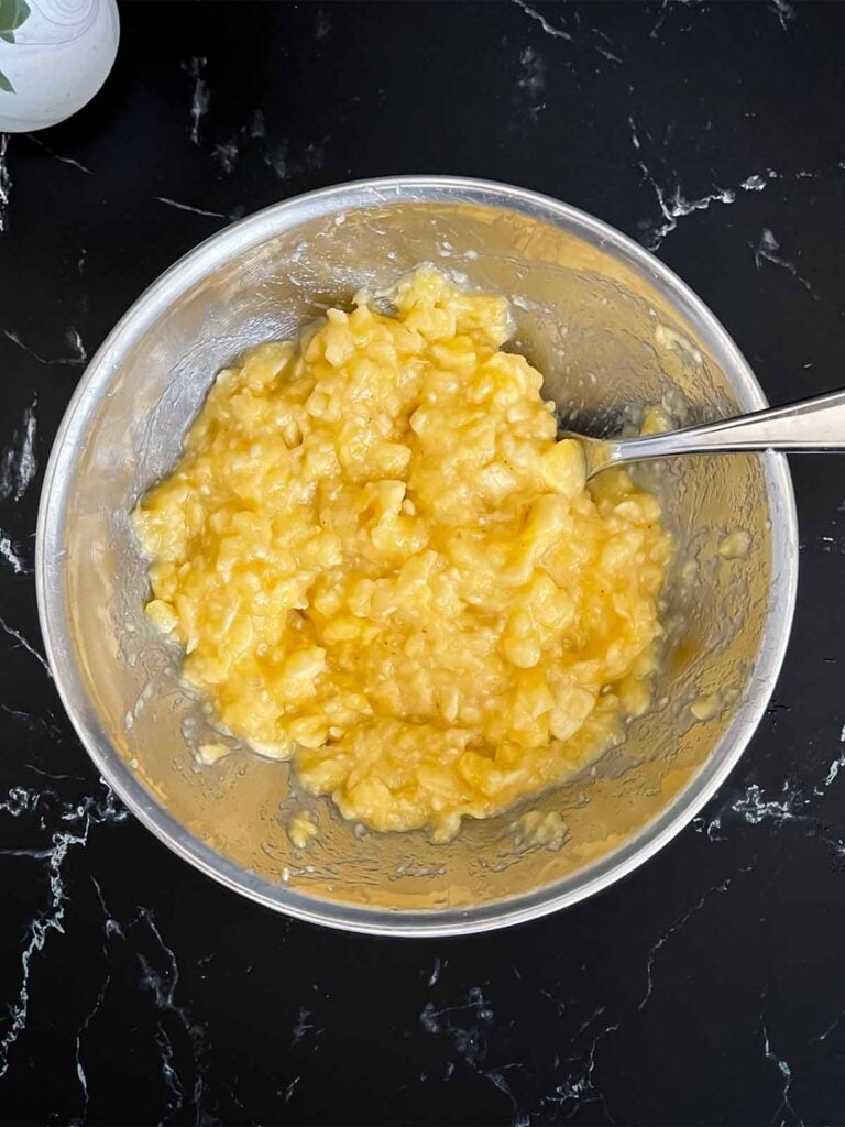 Mashed bananas in a metal bowl for banana bread recipe.