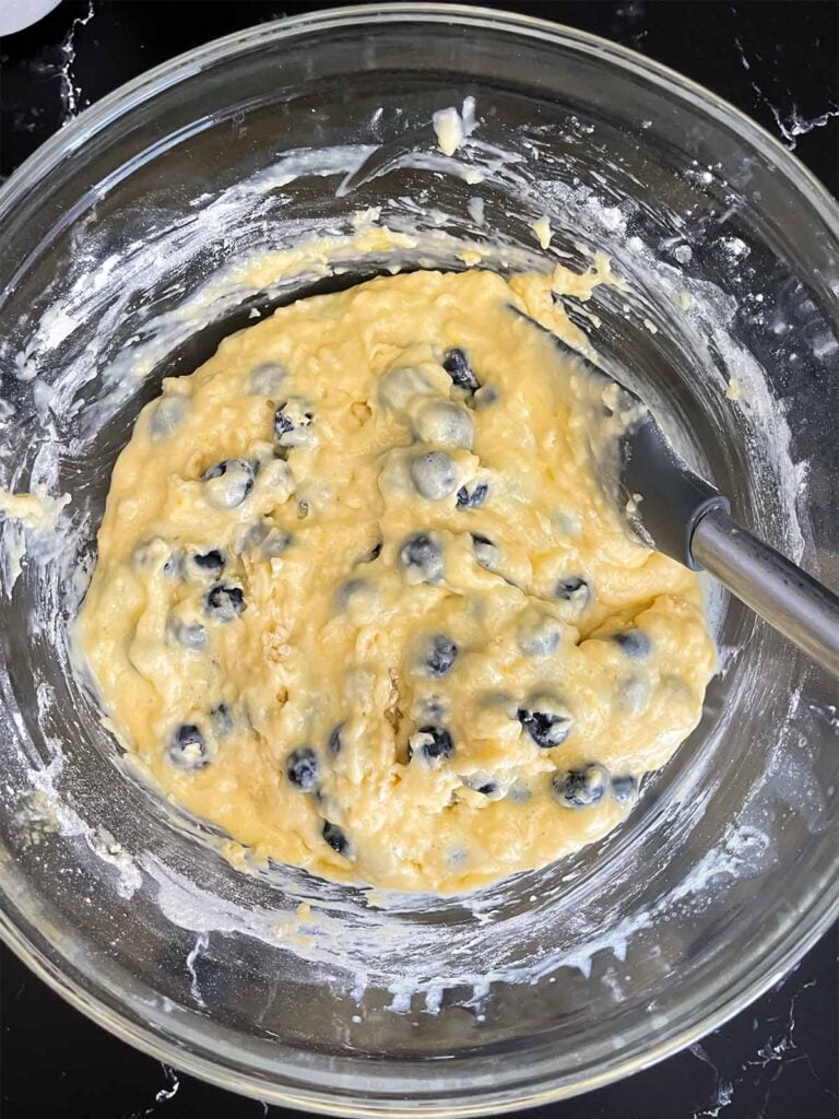 Blueberry bread batter mixed in a glass mixing bowl.
