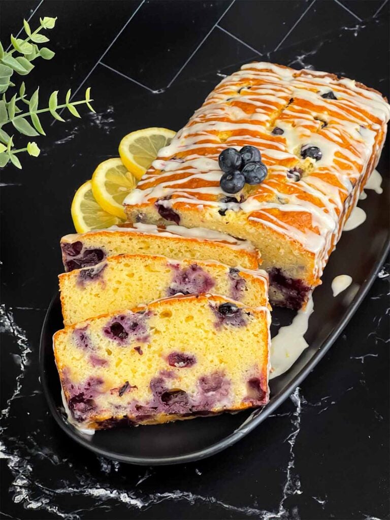 Sliced blueberry bread on a dark platter on a dark surface.