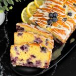 Sliced blueberry bread on a dark platter on a dark surface.