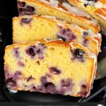 Sliced blueberry bread on a dark platter on a dark surface.