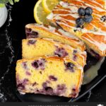 Sliced blueberry bread on a dark platter on a dark surface.