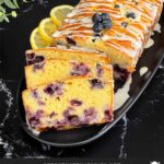 Sliced blueberry bread on a dark platter on a dark surface.